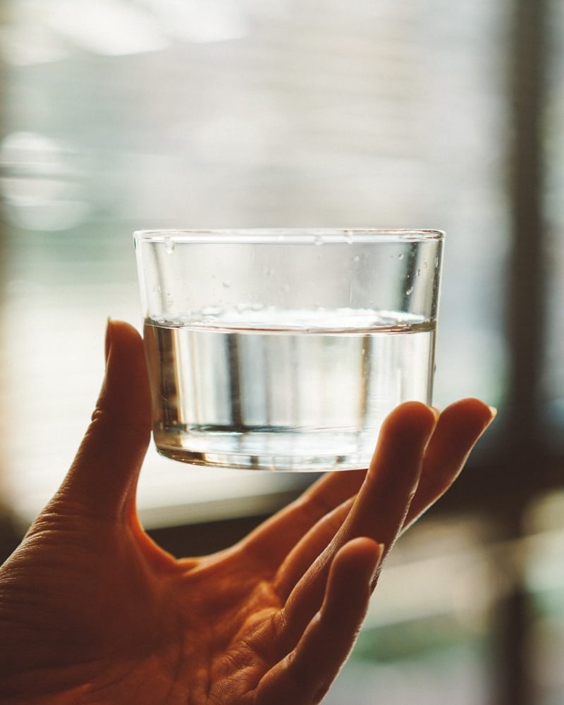 person holding clear glass cup with half-filled water