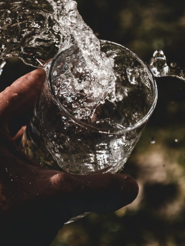 person holding drinking glass filled with water